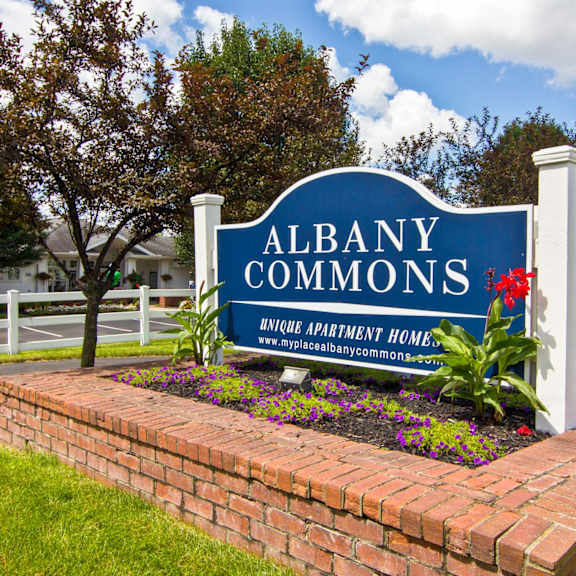 the sign commons in front of a brick retaining wall with flowers