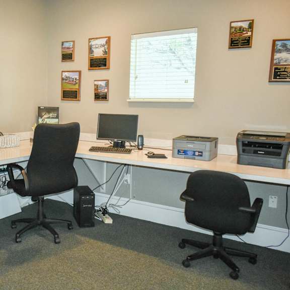 a computer room with three desks and three chairs and a monitor