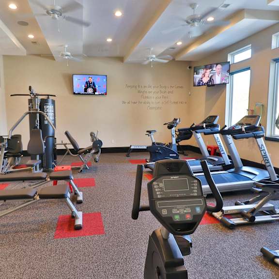a gym with exercise equipment and a tv on the wall