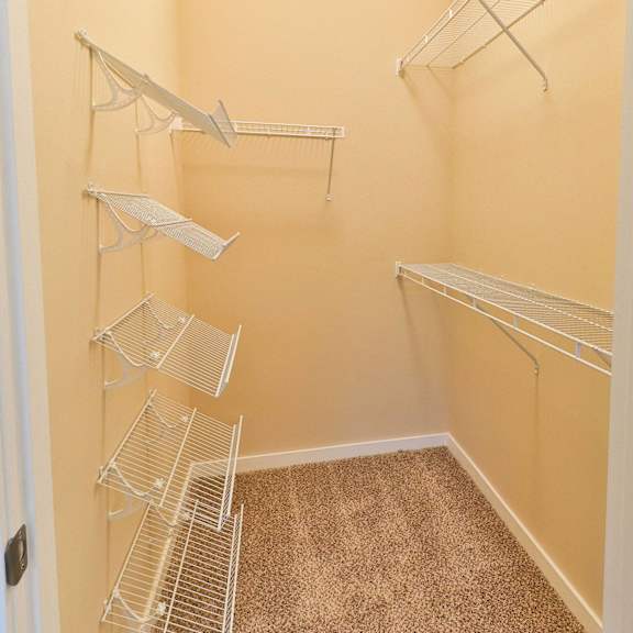 an empty closet with three hanging racks in a closet with a door