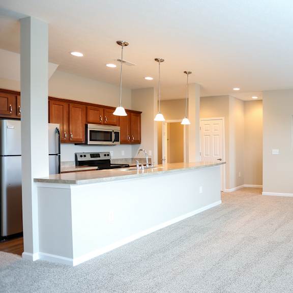 an empty living room and kitchen with a counter top