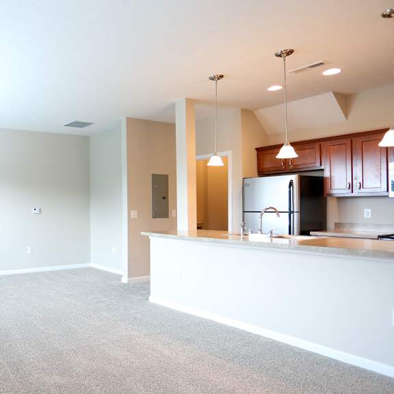an empty living room and kitchen with a counter top