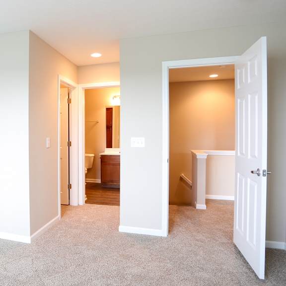 a bedroom with a door open to a bathroom and a closet