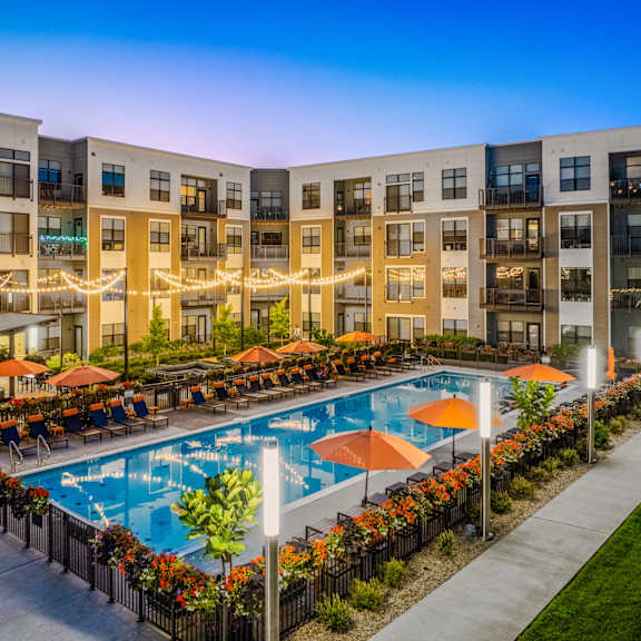 an apartment building with a swimming pool at dusk