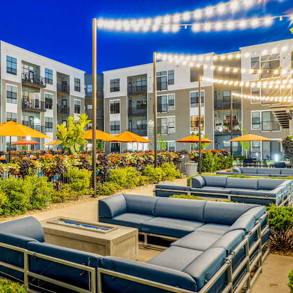 an outdoor patio with lounge chairs and umbrellas at night