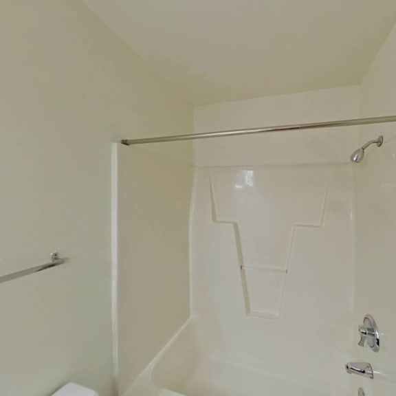 Thumbnail 10 of 10 A white shower stall with a glass door and a metal grab bar.