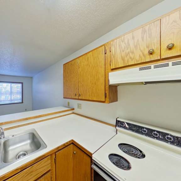 Thumbnail 4 of 10 A kitchen with a stove, sink, and cabinets.