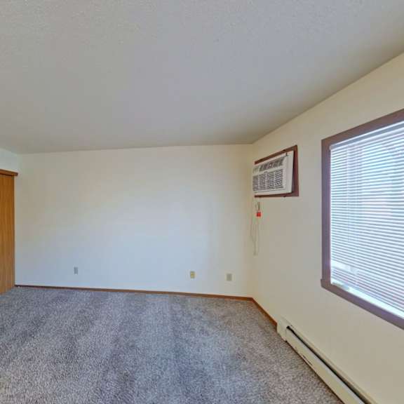 Thumbnail 3 of 10 A room with a carpeted floor and a window with blinds.