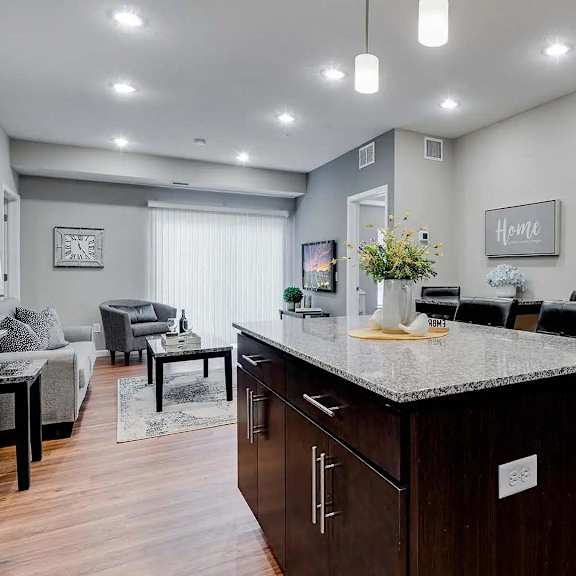 Thumbnail 4 of 10 a kitchen with a counter top and a living room. Circle Pines, MN Lexington Lofts