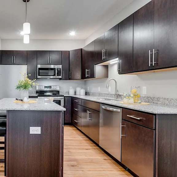 Thumbnail 2 of 10 a kitchen with a island and a table with chairs. Circle Pines, MN Lexington Lofts