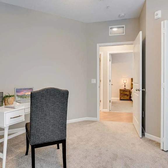 Thumbnail 10 of 12 a bedroom with a desk with a chair and a door to a bathroom.  Circle Pines, MN Lexington Lofts