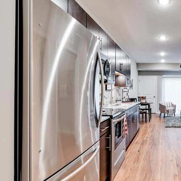 Thumbnail 2 of 7 a kitchen with stainless steel appliances and a door to a living room. Circle Pines, MN Lexington Lofts