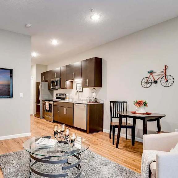Thumbnail 4 of 7 a living room and kitchen with a couch and a table. Circle Pines, MN Lexington Lofts