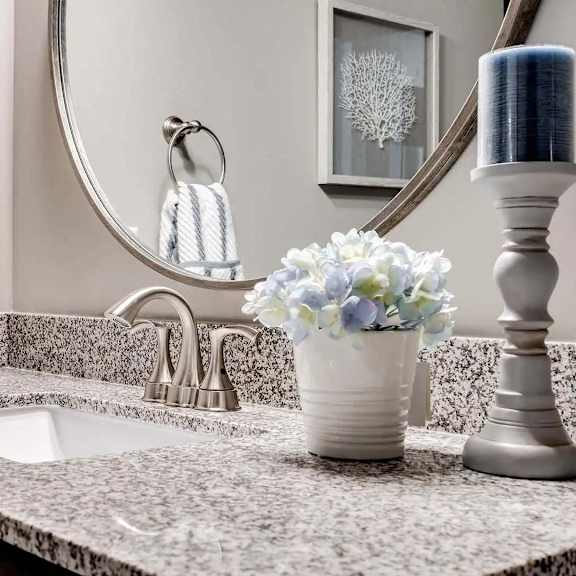 Thumbnail 9 of 9 a bathroom sink with a mirror and a vase with flowers. Circle Pines, MN Lexington Lofts