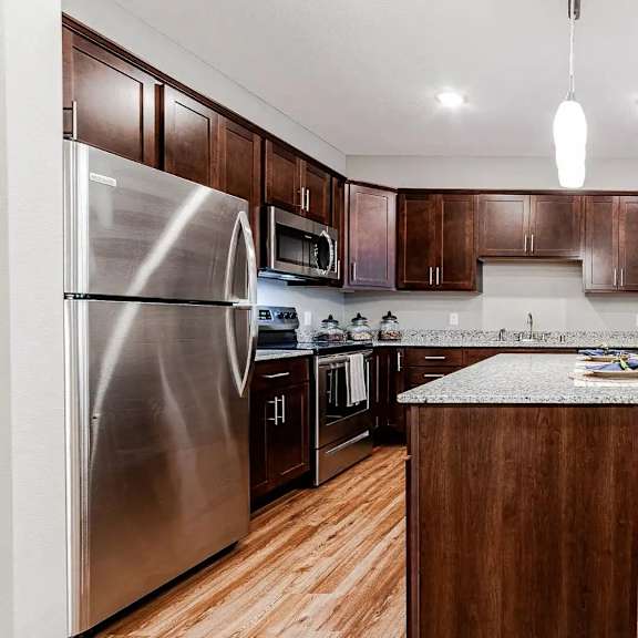 Thumbnail 2 of 2 a large kitchen with stainless steel appliances and a dining table. Circle Pines, MN Lexington Lofts