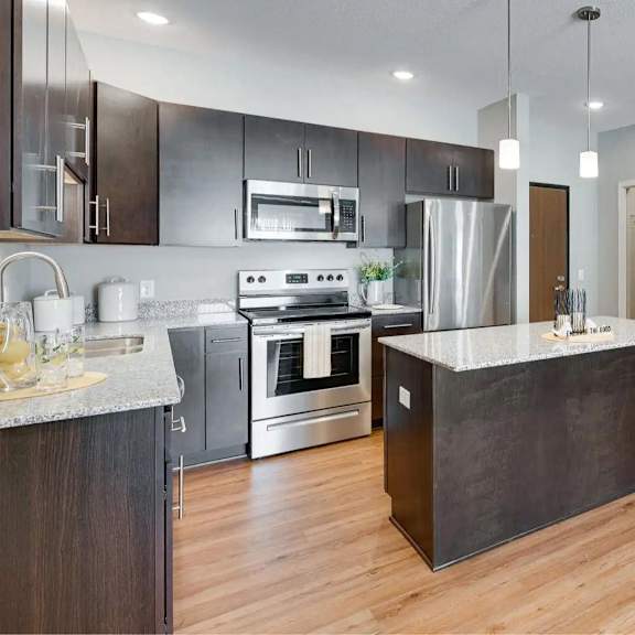 Thumbnail 2 of 8 an open kitchen with a large island in the middle. Circle Pines, MN Lexington Lofts