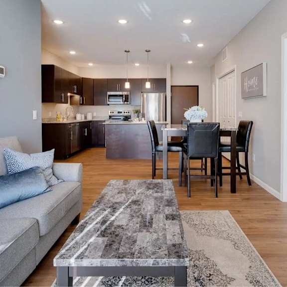Thumbnail 4 of 8 a living room and kitchen with a couch and a table. Circle Pines, MN Lexington Lofts
