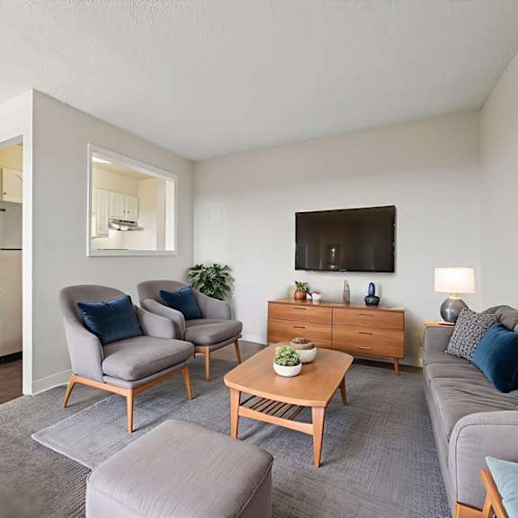 a living room with a grey couch, a wooden coffee table, and a painting on the wall.