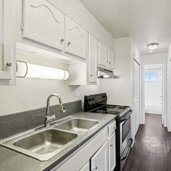 a kitchen with white cabinets and a stainless steel sink.