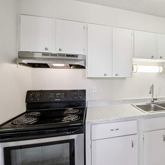 a kitchen with white cabinets and a black stove top oven.