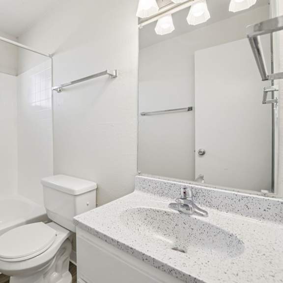 a white bathroom with a toilet, sink, and bathtub.