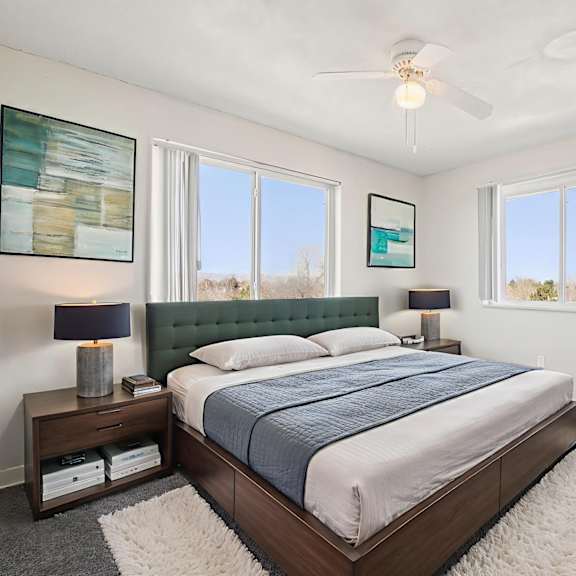 a bedroom with a bed, nightstand, and a ceiling fan.