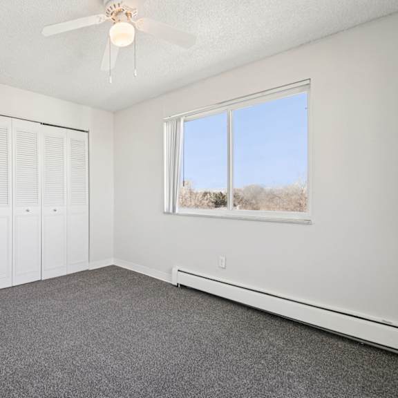 a room with a ceiling fan and a window overlooking a snowy landscape.