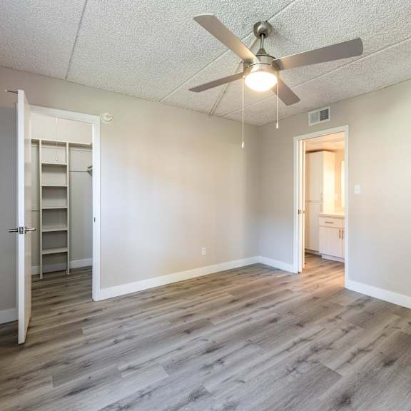 an empty living room with a ceiling fan and a closet