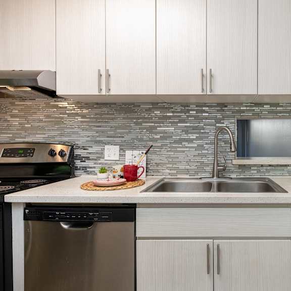 a kitchen with white cabinets and a stainless steel sink