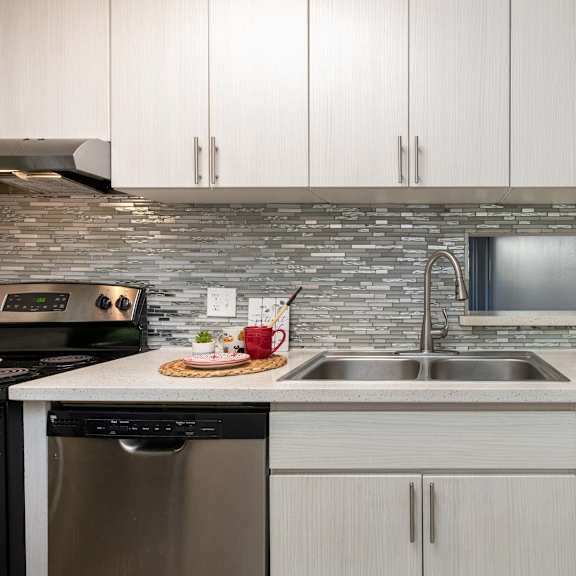 a kitchen with white cabinets and a stainless steel sink