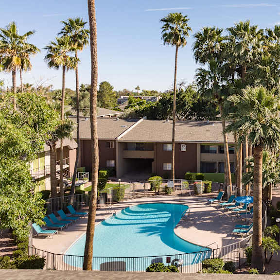 an aerial view of a resort with a swimming pool and palm trees