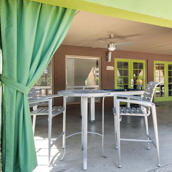 a patio with a table and chairs and a green curtain