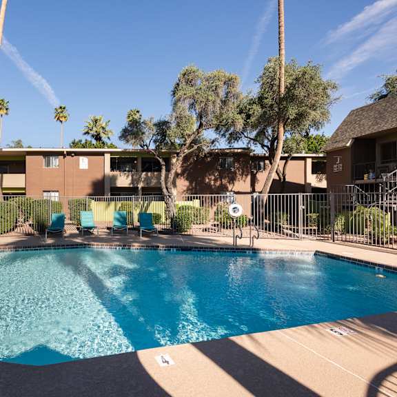 a swimming pool with chairs in front of a building