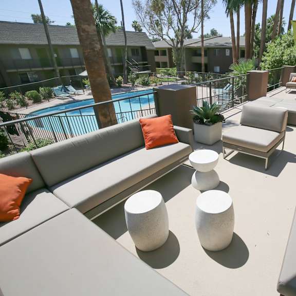 a large patio with couches and tables and a pool