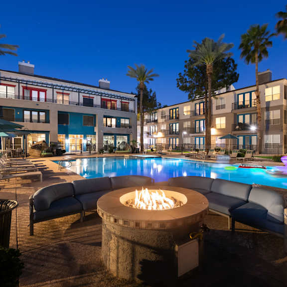 a poolside area with a fire pit in the middle of the pool.
