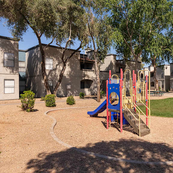 a playground with a swing set and slides in front of a building