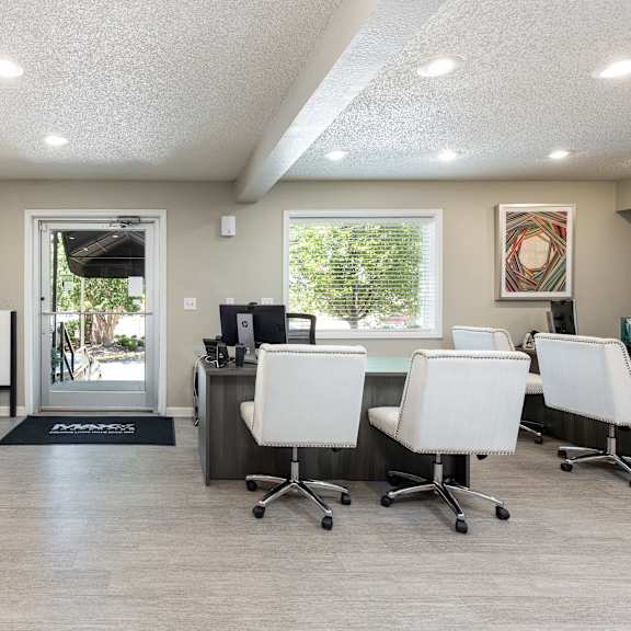 a break room with white chairs and a desk and a doorway