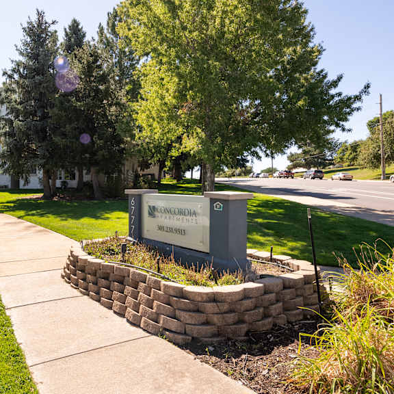 a sidewalk in front of a building with trees and grass