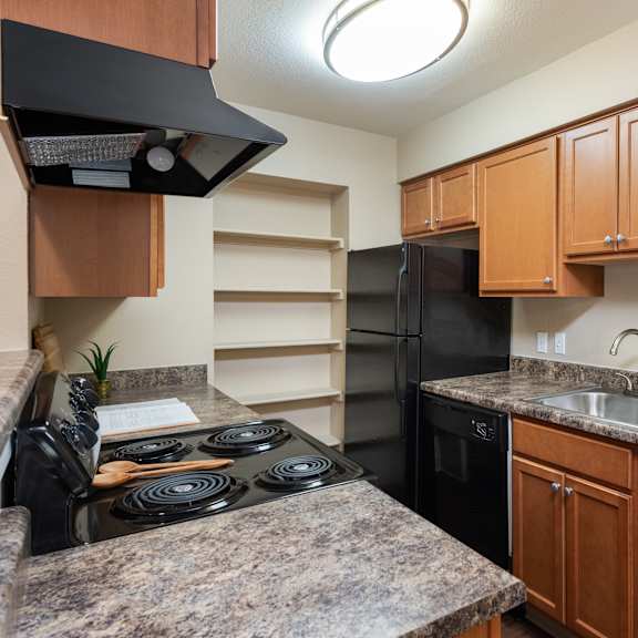 a kitchen with black appliances and granite counter tops and wooden cabinets