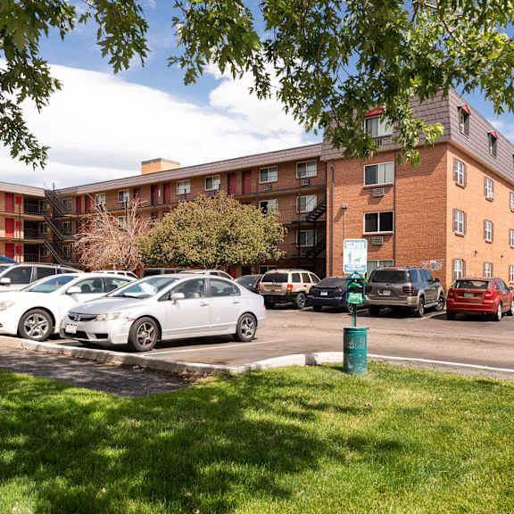 a parking lot with cars in front of an apartment building