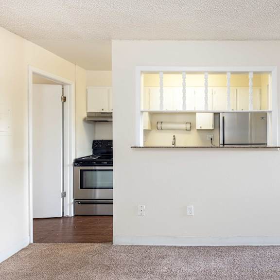 an empty living room and kitchen with a hard wood floor