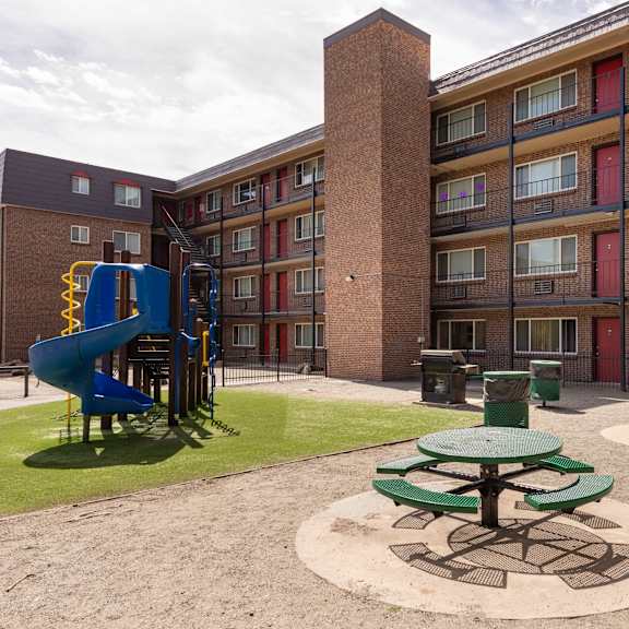 a playground in the courtyard of an apartment building with a blue slide