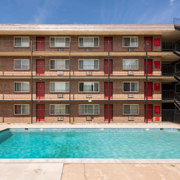 the pool is in front of a red brick building with a swimming pool