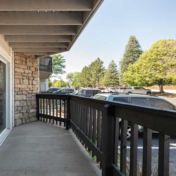 the porch of a building with a balcony and cars in the parking lot