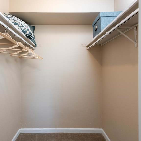a walk in closet with shelves and a bed in it
