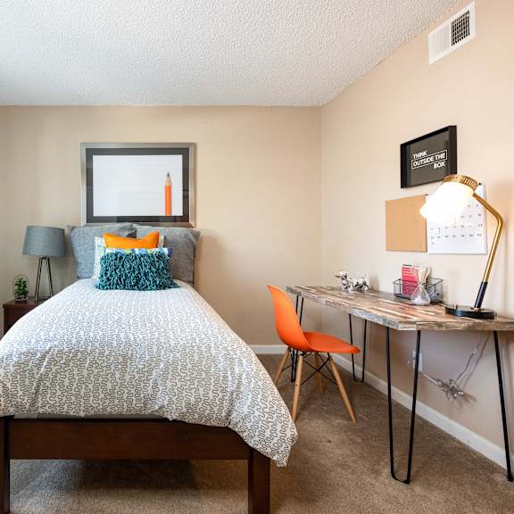 a bedroom with a bed and a desk and a window