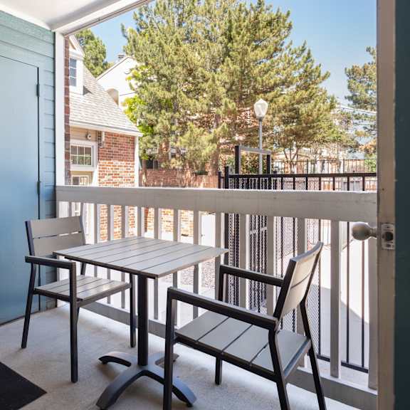 a balcony with a table and chairs and a blue door