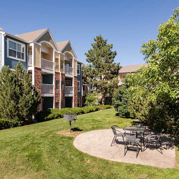 a patio with a table and chairs in front of an apartment building