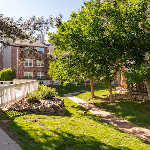 a sidewalk and trees in front of a brick building
