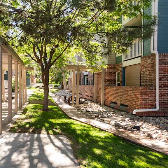 a sidewalk in front of a brick building with trees